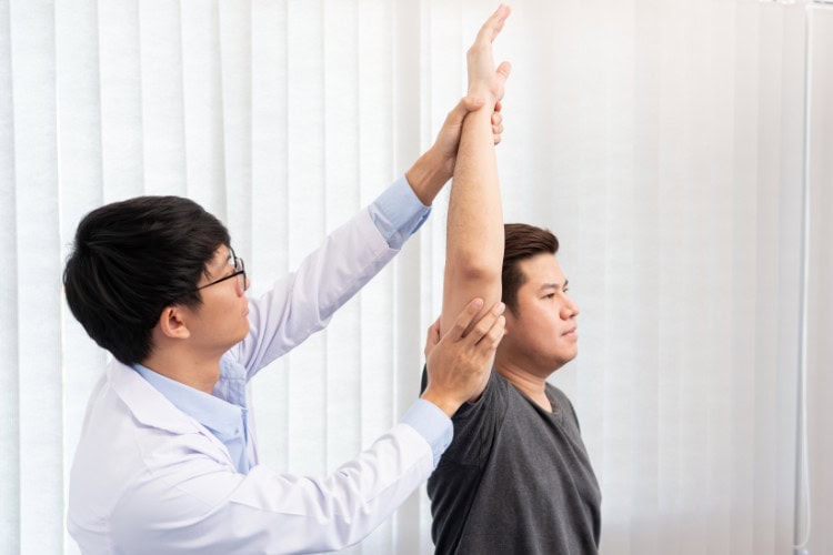 Physiotherapist assessing patients shoulder mobility in clinic - One Body LDN Physiotherapist assessing patient’s shoulder mobility in clinic