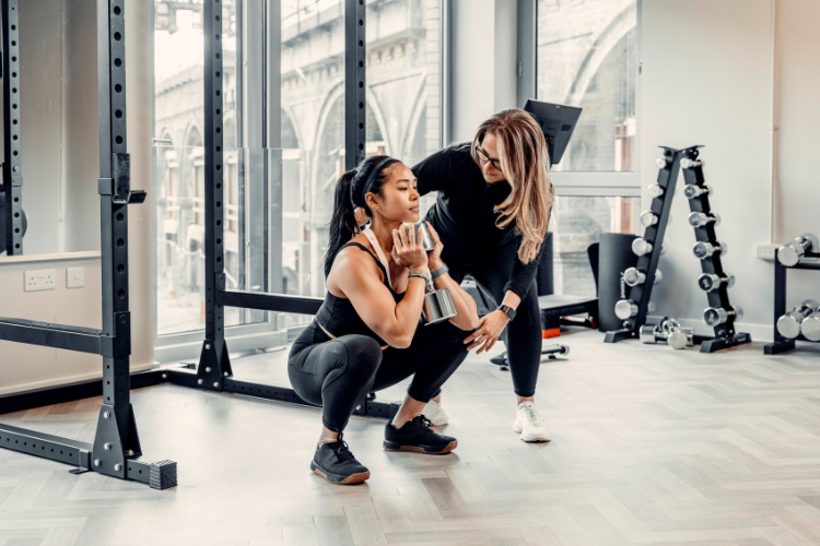 Trainer supervising woman’s squat exercise for posture and strength