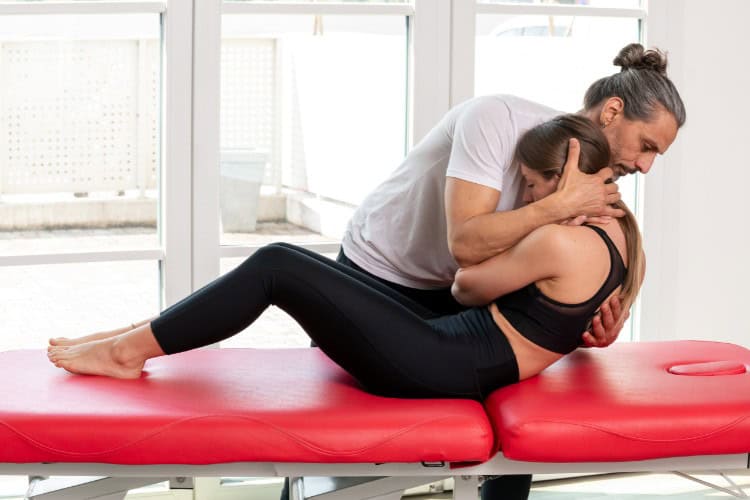 Types of Physiotherapy Explained - One Body LDN Spinal adjustment therapy on red treatment table