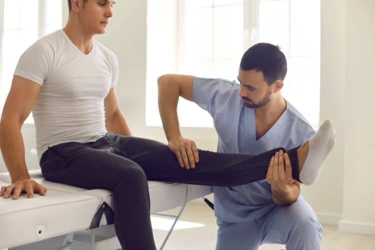 Physiotherapist assessing patients knee at Joint Injections Clinic