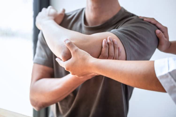 2 Therapist assisting man with arm mobility at hand clinic - One Body LDN Therapist assisting man with arm mobility at Giles Bantick hand clinic