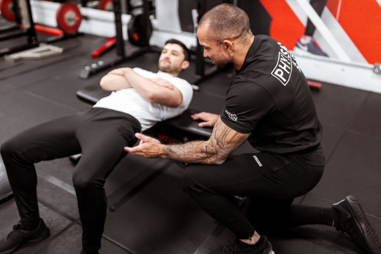 Physio guiding hip bridge exercise with focus and strength