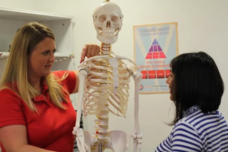 Nell Mead Physiotherapist explaining spine anatomy with skeleton model