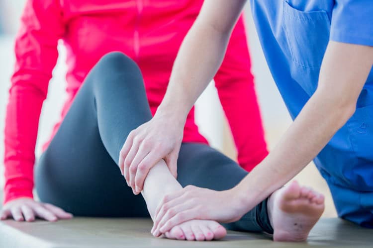 7 Physiotherapist assessing ankle injury during patient rehabilitation session - One Body LDN Physiotherapist assessing ankle injury during patient rehabilitation session