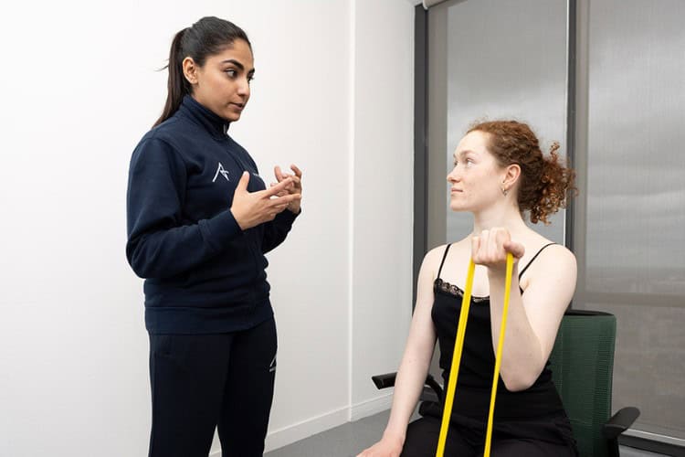 Ascenti physiotherapist guiding patient through resistance band exercise
