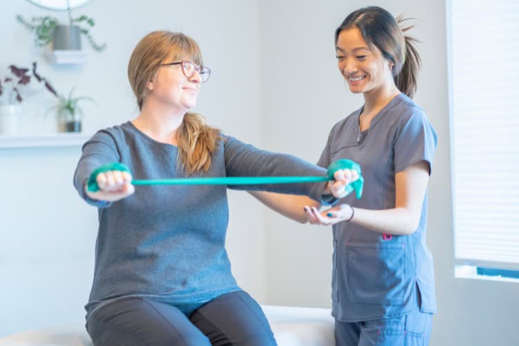 Ascenti physiotherapist guiding shoulder rehab with resistance band - One Body LDN Ascenti physiotherapist guiding shoulder rehab with resistance band