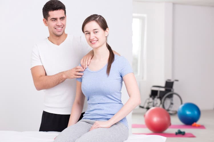Bodyset physiotherapist helping smiling patient with shoulder rehab - One Body LDN Bodyset physiotherapist helping smiling patient with shoulder rehab