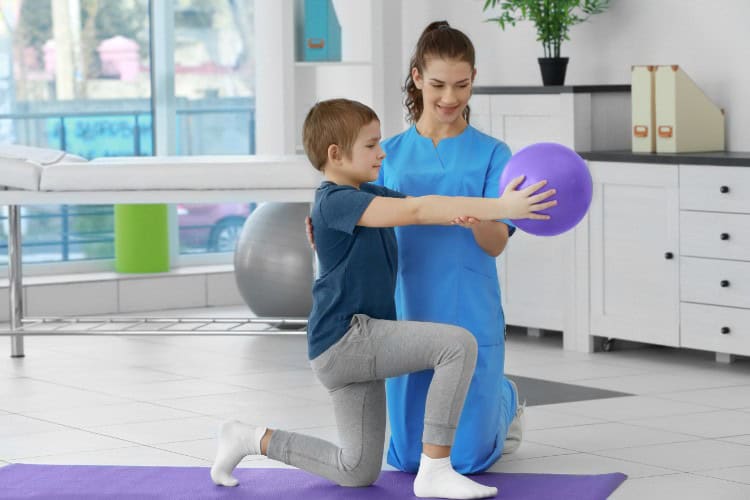 Child receiving physiotherapy with balance ball in caring clinic setting