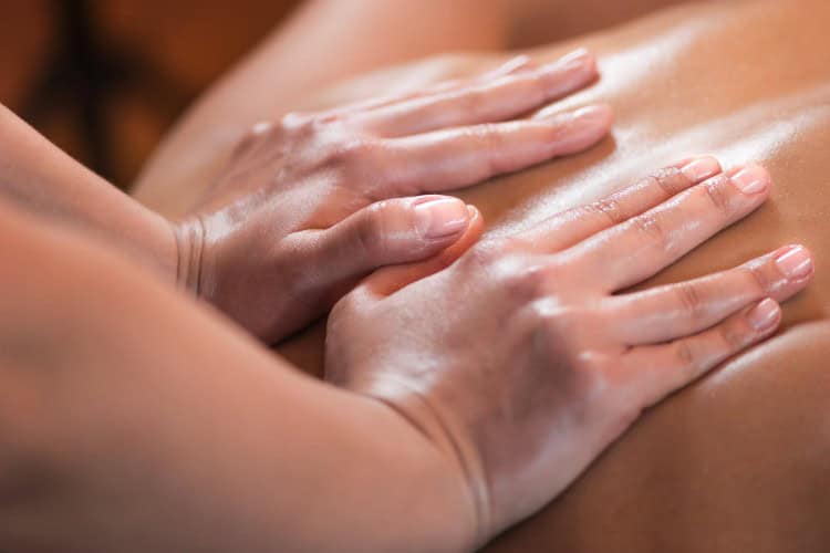 Close-up of hands applying sports massage on oiled back - One Body LDN Close-up of hands applying sports massage on oiled back