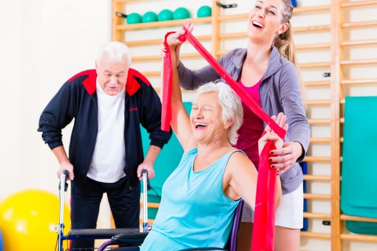 Elderly woman enjoying physical therapy with resistance band support
