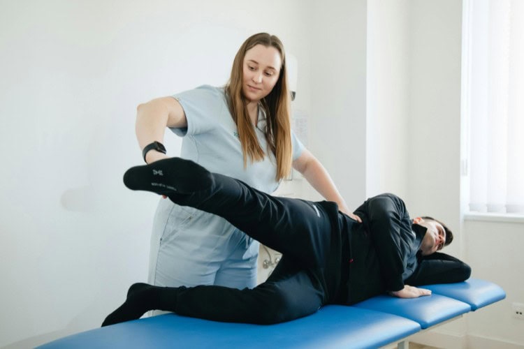 Physiotherapist assisting man with leg rehab at London clinic