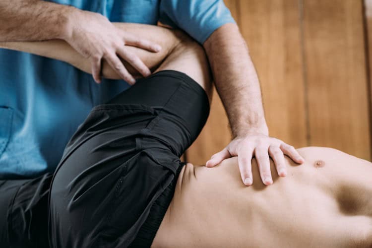 Licensed physiotherapist performing hip mobilization during sports therapy - One Body LDN Licensed physiotherapist performing hip mobilization during sports therapy