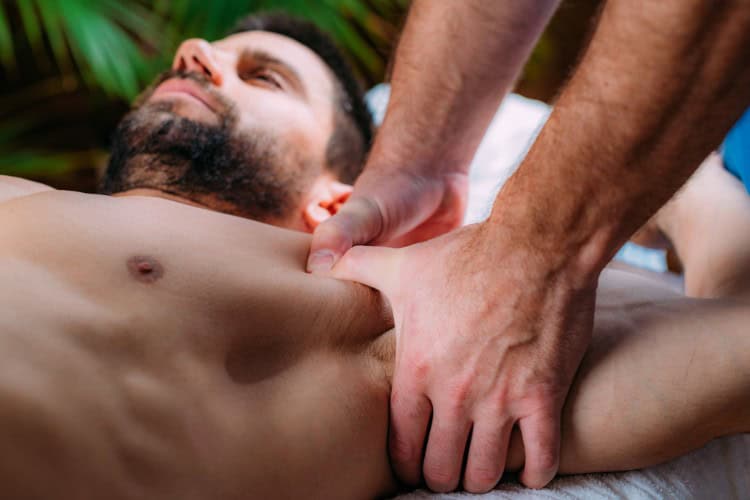 Male client receiving focused shoulder massage in sports therapy session - One Body LDN Male client receiving focused shoulder massage in sports therapy session