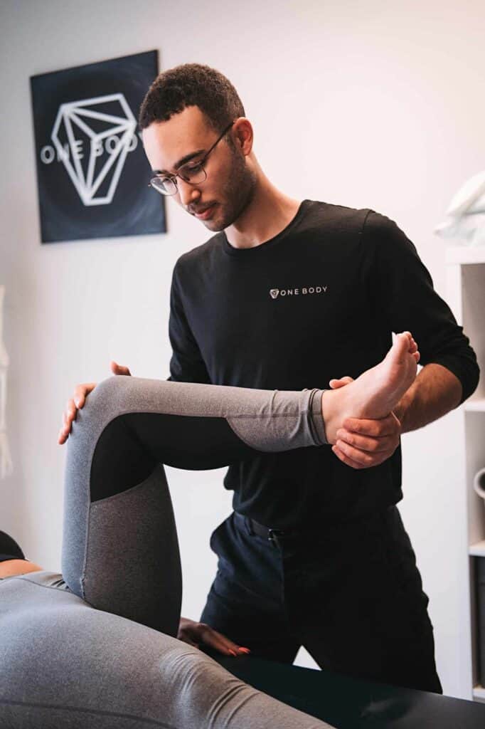 One Body physio guiding patient through leg mobility rehabilitation exercise