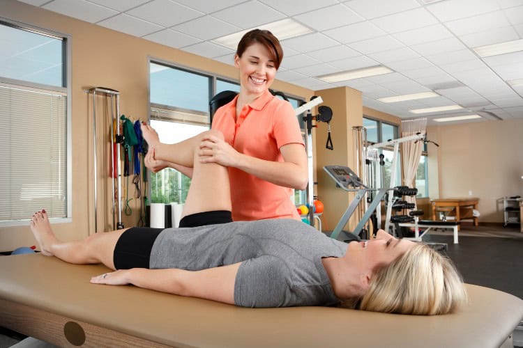 Physical therapist helping woman with leg mobility and flexibility treatment