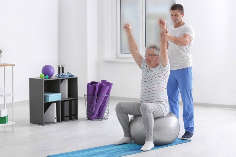 Physiotherapist assisting senior with balance and mobility rehab session