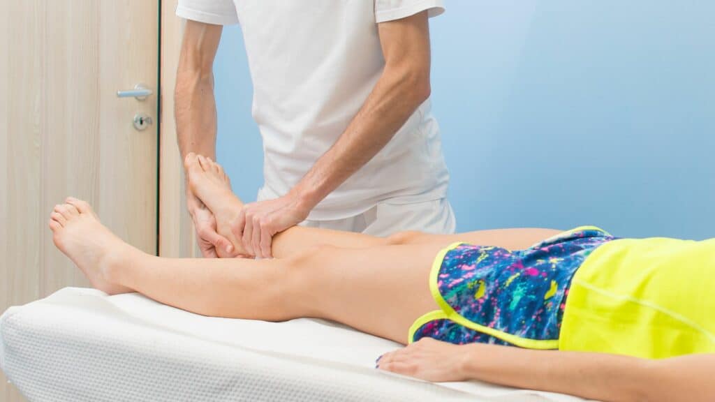 Physiotherapist performing ankle massage therapy on female athlete