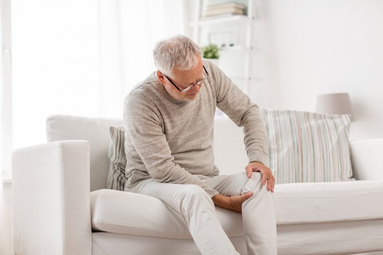 Senior man sitting with visible knee pain discomfort