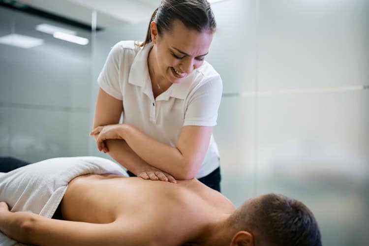 Smiling therapist applying deep tissue pressure during massage session