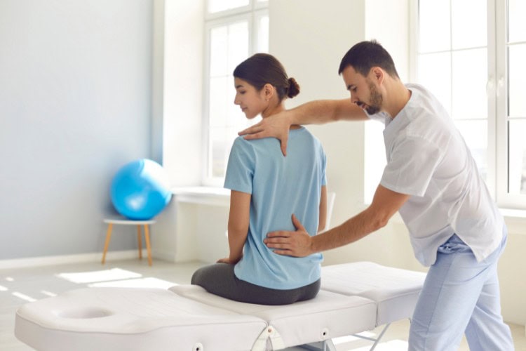 Sports massage therapist assessing posture for injury prevention - One Body LDN Sports massage therapist assessing posture for injury prevention