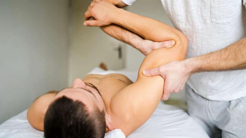Sports massage therapist stretching athlete’s arm to boost performance