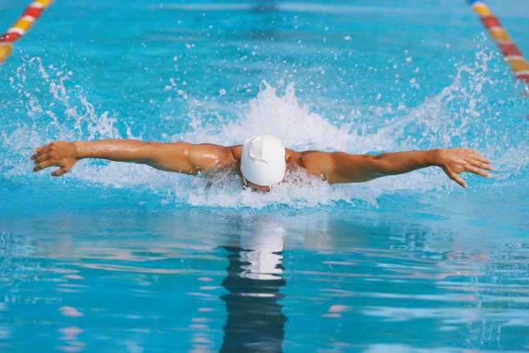 Swimmer showcasing power and focus supported by sports massage - One Body LDN Swimmer showcasing power and focus supported by sports massage