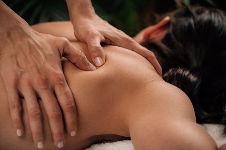Therapist applying deep pressure to shoulder muscle area - One Body LDN Therapist applying deep pressure to shoulder muscle area