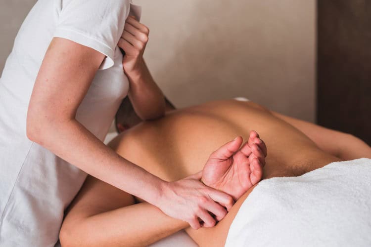 Therapist applying deep sports massage on shoulder joint - One Body LDN Therapist applying deep sports massage on shoulder joint