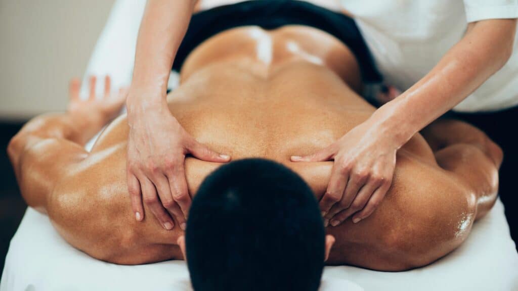 Therapist performing deep tissue massage on male client’s back