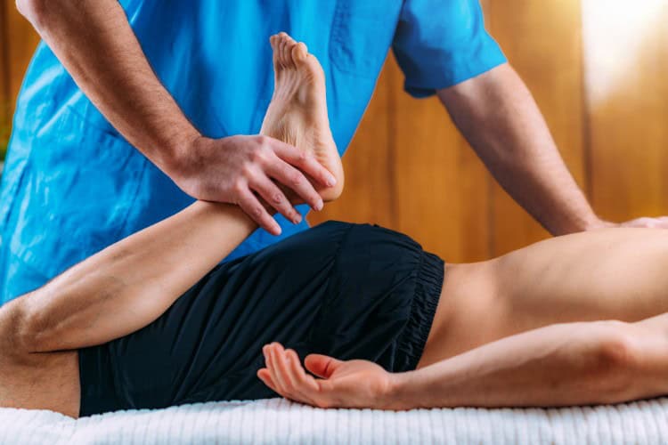 Therapist stretching leg to improve circulation and oxygen delivery