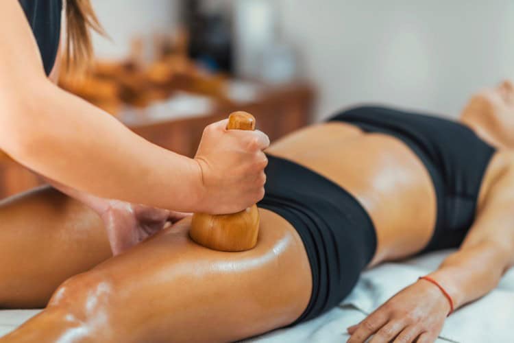 Therapist using wooden tool for deep tissue leg massage