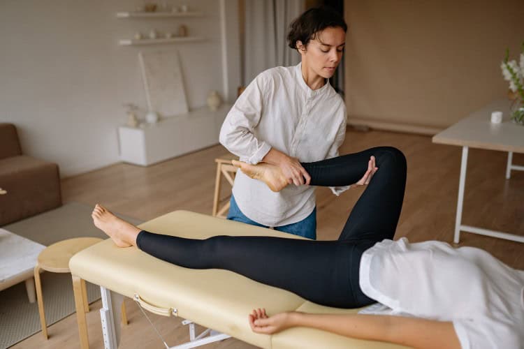 What Qualifies a Sports Massage Therapist - One Body LDN Therapist assessing client’s leg mobility during sports massage training