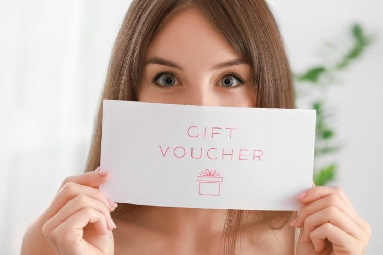 Woman holding London sports massage gift voucher with excitement