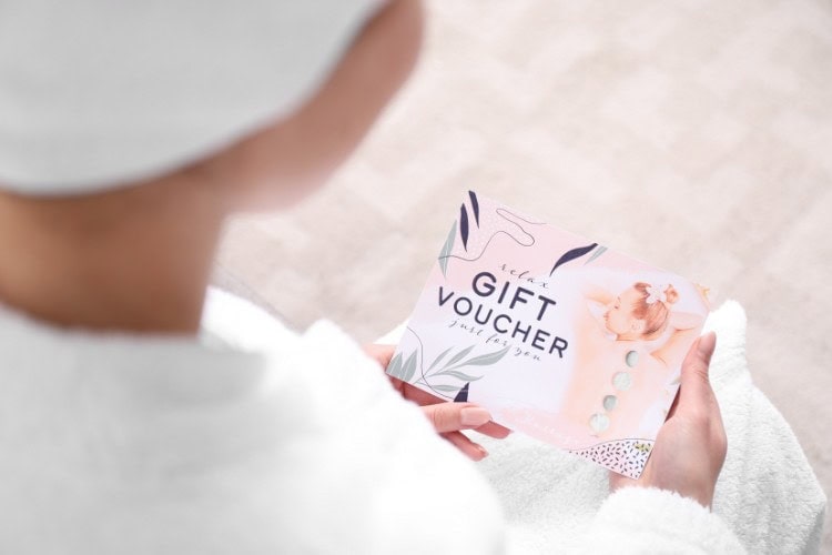 Woman in robe holding London sports massage gift voucher