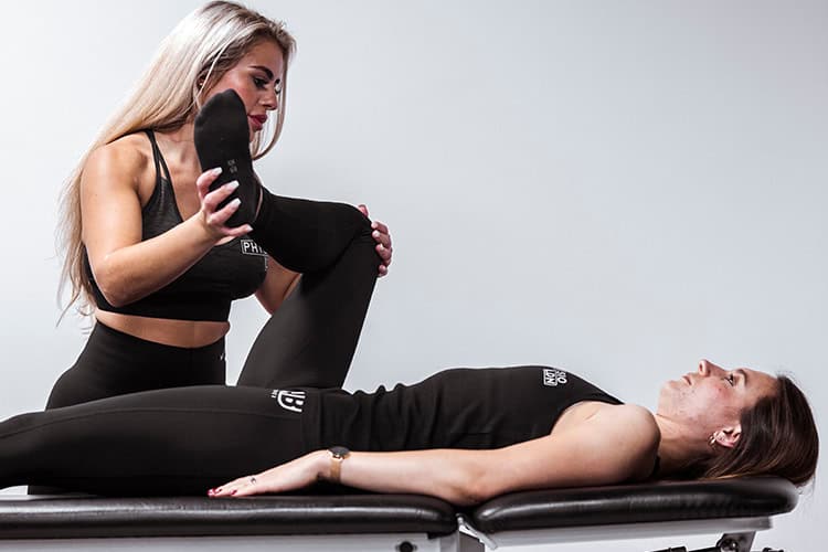 Physiotherapist treating ankle pain with guided leg stretch