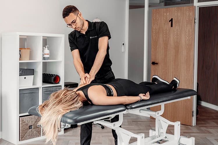 Sports massage therapist treating client’s back for recovery benefits