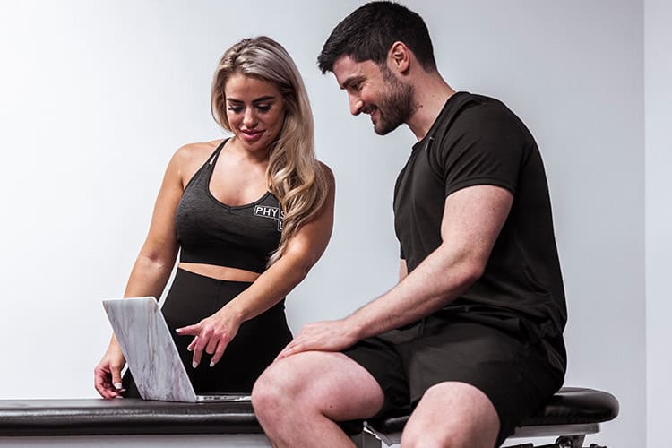 Physiotherapist showing treatment progress on laptop to client during consultation for consistent reviews