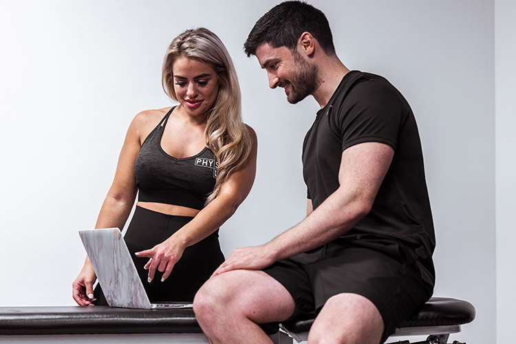 Physiotherapist showing treatment progress on laptop to client during consultation for consistent reviews
