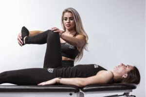 Sports physiotherapist guiding leg stretch therapy session